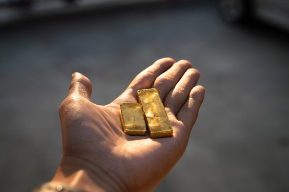 Man holding gold bars.
